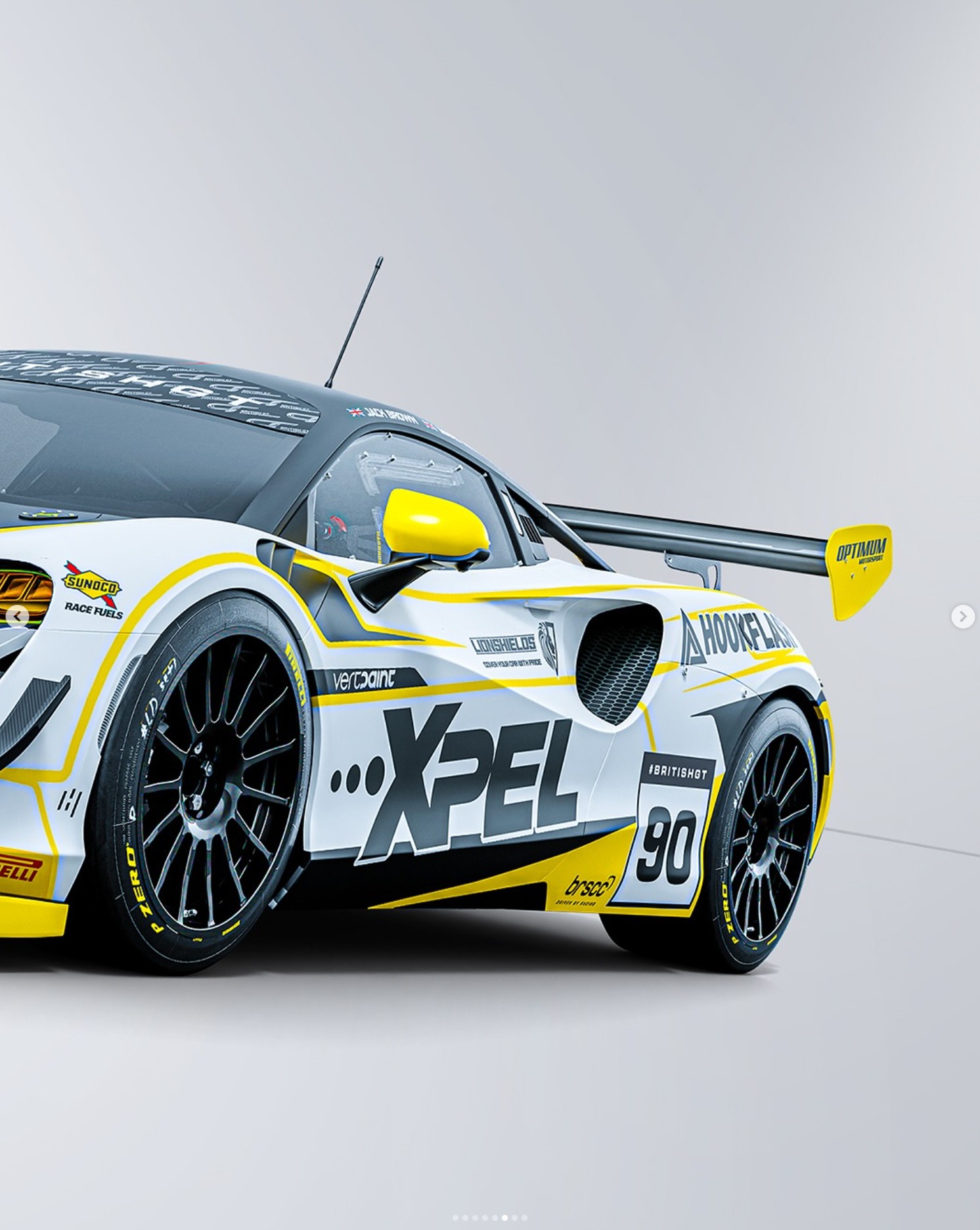 The rear half of the white and yellow number 90 McLaren, with the Vertpaint wordmark above its side intake
