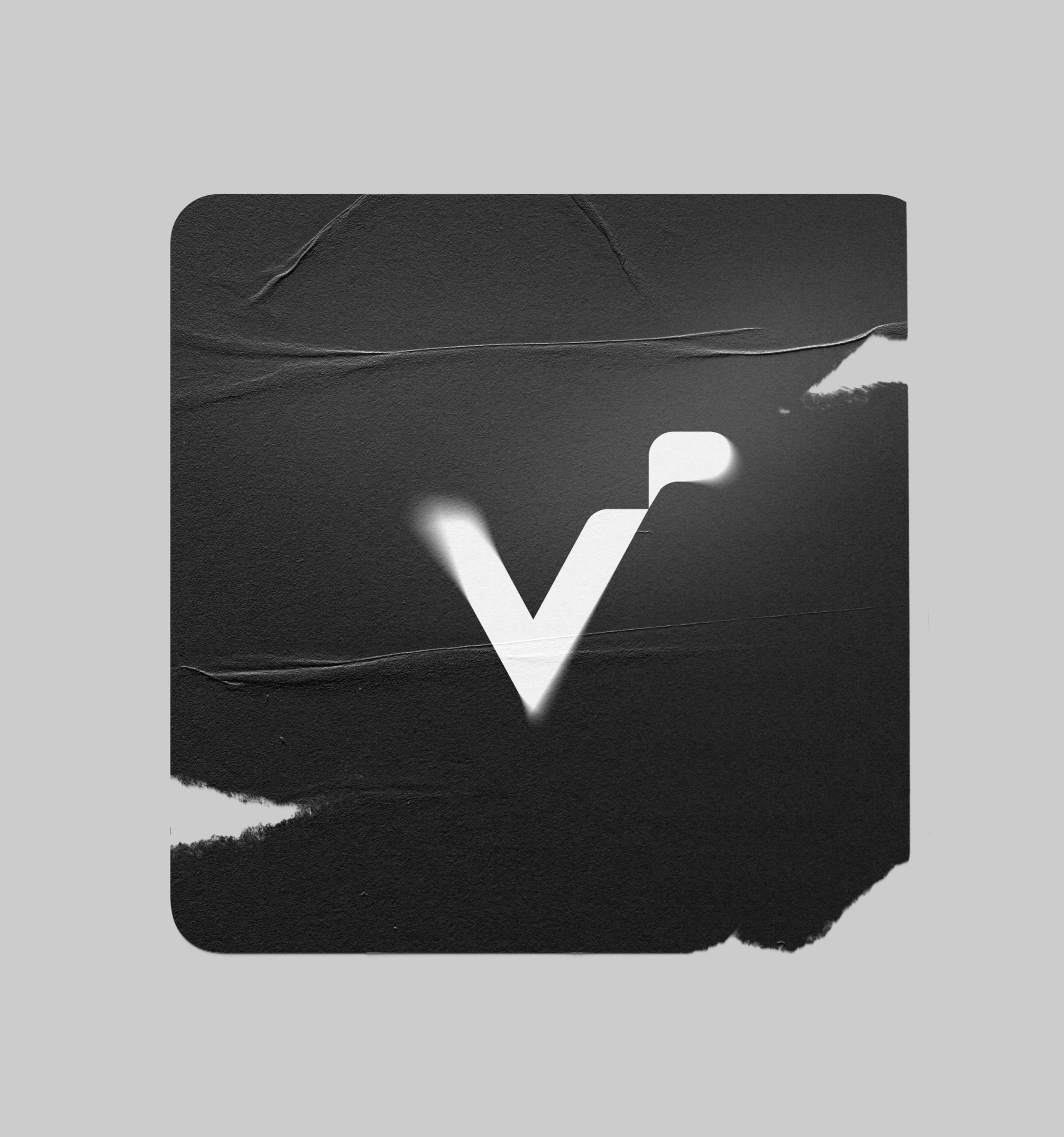 A torn Vertpaint V icon sticker on a wall